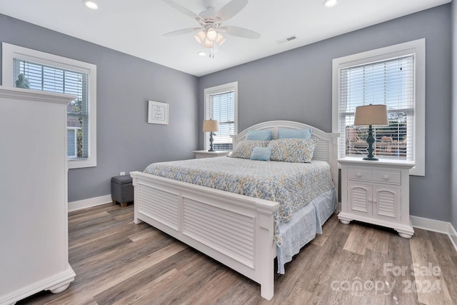 bedroom featuring ceiling fan, multiple windows, and hardwood / wood-style floors