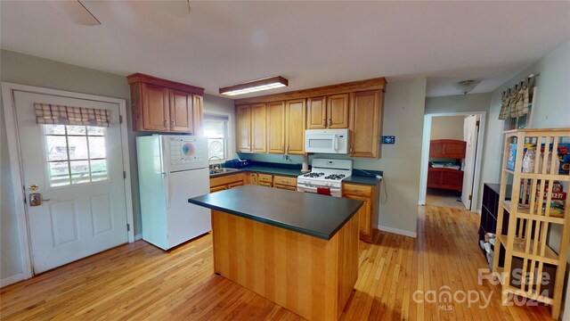 kitchen with sink, white appliances, light hardwood / wood-style floors, and a center island