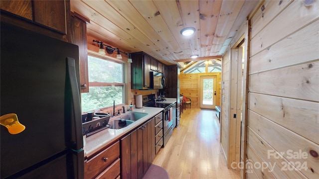 kitchen featuring light wood-type flooring, wood ceiling, wooden walls, sink, and stainless steel appliances