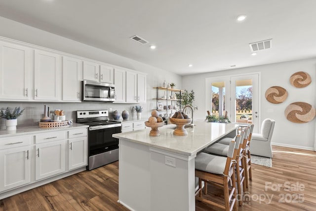 kitchen featuring white cabinetry, stainless steel appliances, and an island with sink