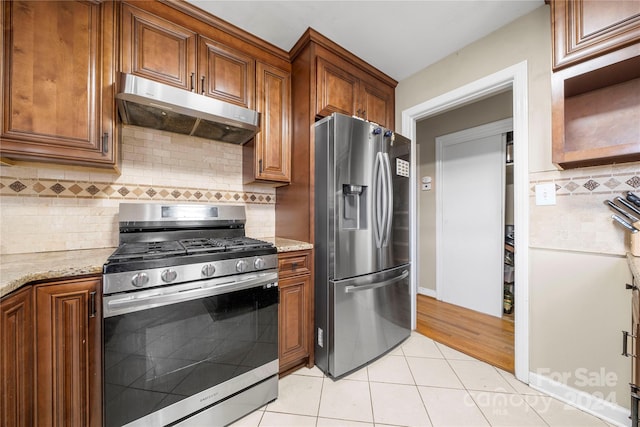 kitchen with decorative backsplash, light hardwood / wood-style flooring, appliances with stainless steel finishes, and light stone counters