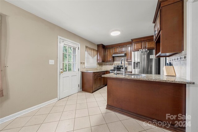 kitchen with backsplash, stainless steel appliances, sink, light stone counters, and light tile patterned floors