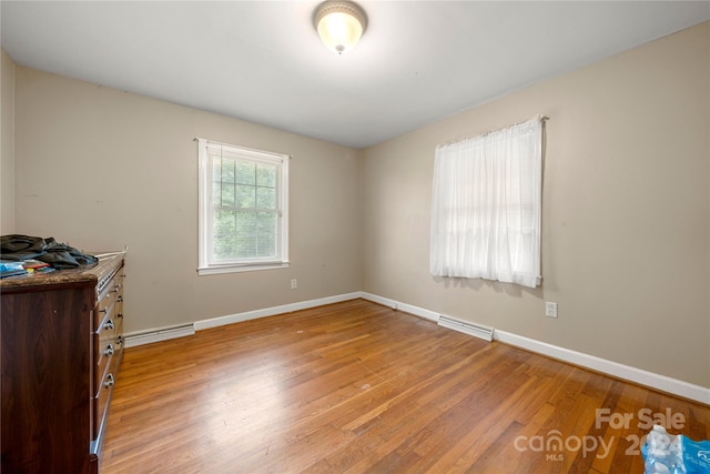 bedroom with hardwood / wood-style floors and baseboard heating