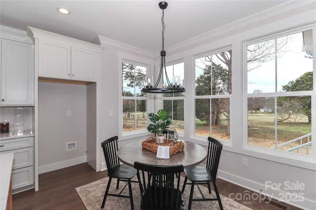 dining space featuring crown molding, dark wood-style floors, visible vents, and baseboards