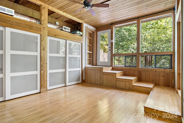 unfurnished sunroom with ceiling fan, wood ceiling, and a healthy amount of sunlight