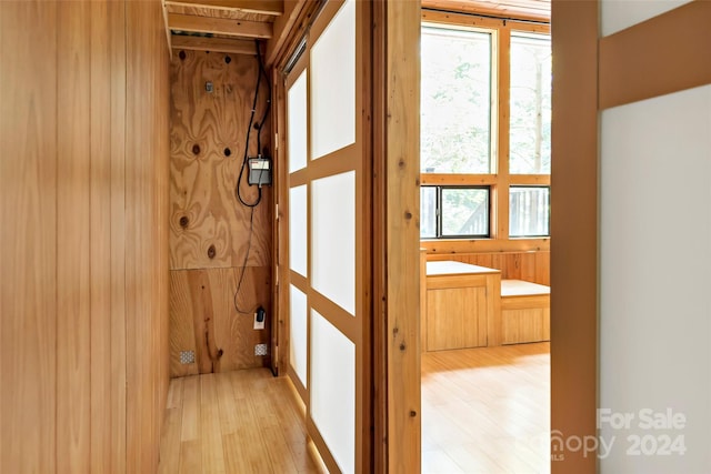 hallway with light hardwood / wood-style floors and wooden walls