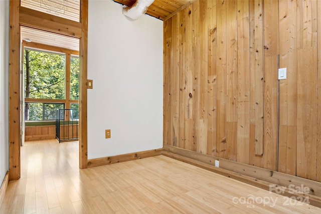 unfurnished room with wooden walls, light wood-type flooring, and wooden ceiling