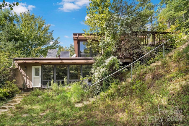 back of house with a sunroom and solar panels