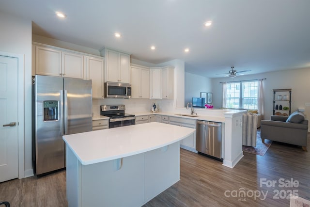 kitchen with a breakfast bar, a center island, kitchen peninsula, white cabinetry, and stainless steel appliances