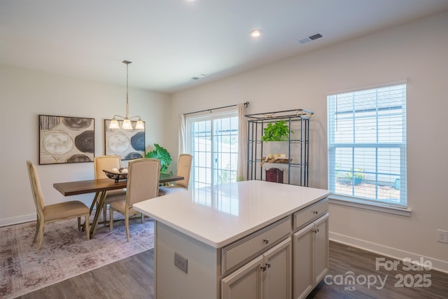 kitchen with gray cabinetry, dark wood-type flooring, hanging light fixtures, an inviting chandelier, and a kitchen island