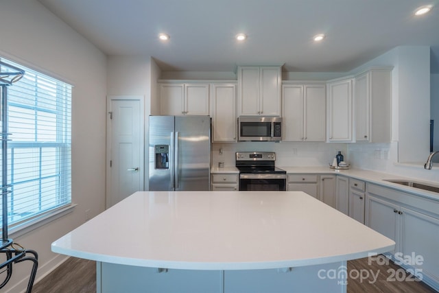 kitchen featuring backsplash, stainless steel appliances, a kitchen island, and sink