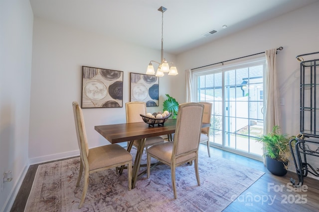 dining area with hardwood / wood-style floors and an inviting chandelier