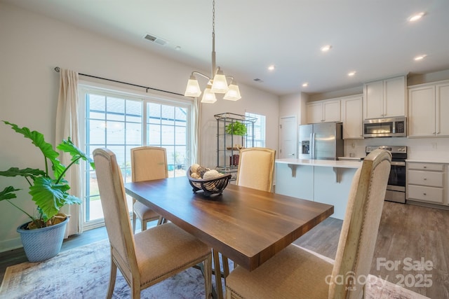 dining space with light hardwood / wood-style floors and an inviting chandelier