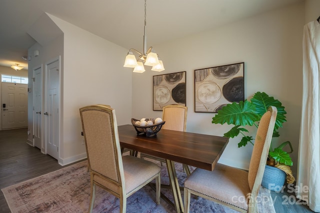 dining space with dark hardwood / wood-style flooring and a chandelier