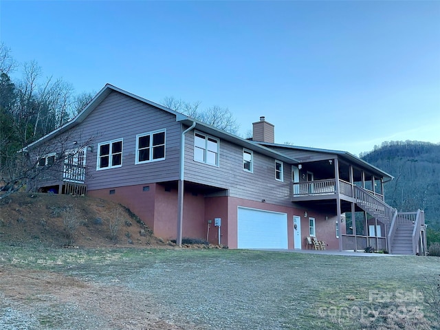 back of property with a yard, a deck, and a garage