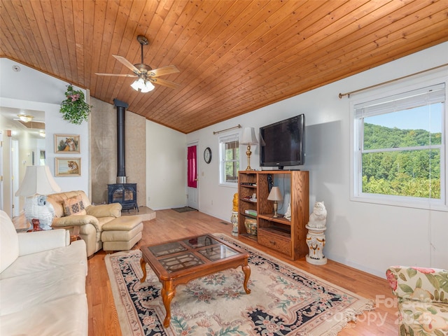 living room featuring wooden ceiling, a wood stove, vaulted ceiling, ceiling fan, and light wood-type flooring