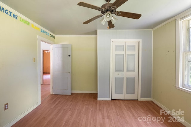 unfurnished bedroom featuring light wood-type flooring, crown molding, ceiling fan, and a closet