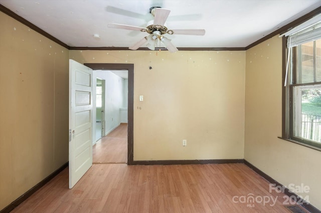 unfurnished room with a wealth of natural light, ornamental molding, and light hardwood / wood-style flooring