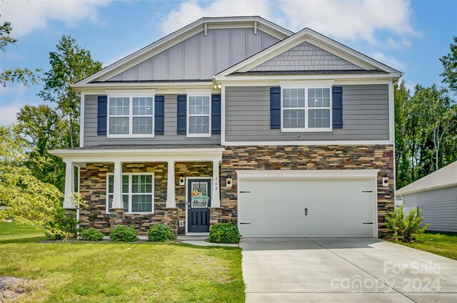 craftsman-style house with an attached garage, board and batten siding, stone siding, driveway, and a front lawn