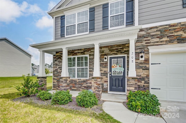 property entrance featuring a garage, stone siding, and a porch