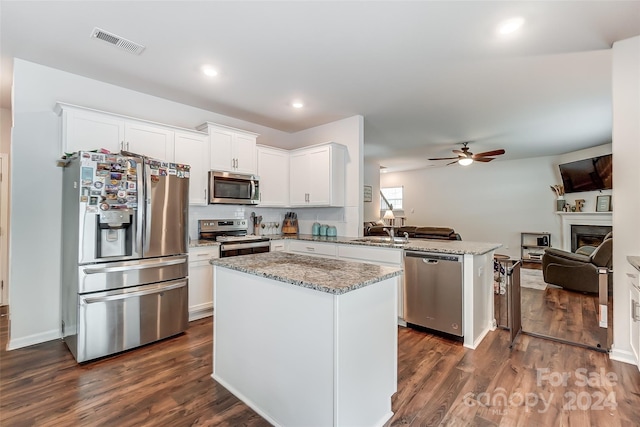 kitchen with white cabinets, open floor plan, a center island, a peninsula, and stainless steel appliances