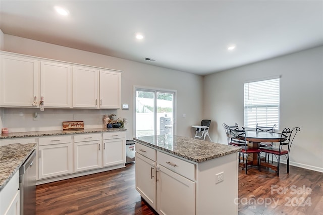 kitchen featuring white cabinets, a kitchen island, visible vents, and light stone countertops