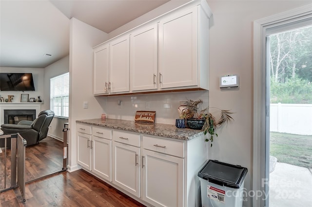 kitchen featuring a glass covered fireplace, dark wood-style floors, open floor plan, stone counters, and white cabinetry