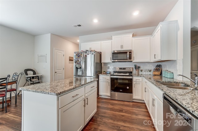 kitchen featuring light stone counters, stainless steel appliances, visible vents, white cabinets, and a sink