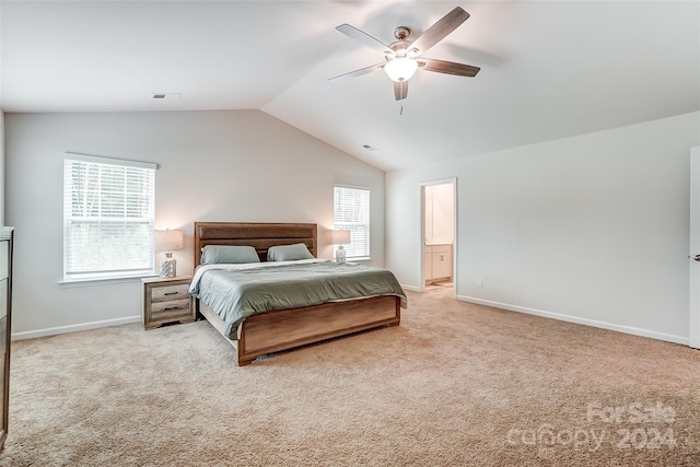 bedroom with light carpet, baseboards, a ceiling fan, ensuite bath, and vaulted ceiling