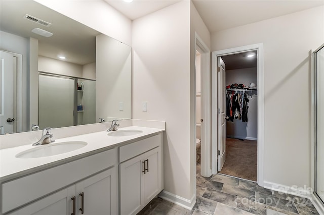 bathroom with a shower stall, a spacious closet, visible vents, and a sink