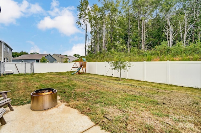 view of yard with an outdoor fire pit, a playground, and a fenced backyard