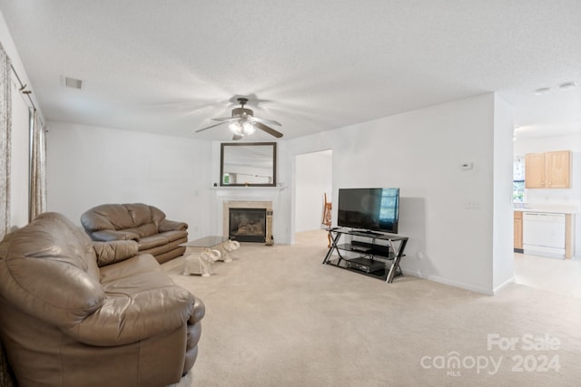 living room with ceiling fan, light colored carpet, a high end fireplace, and a textured ceiling