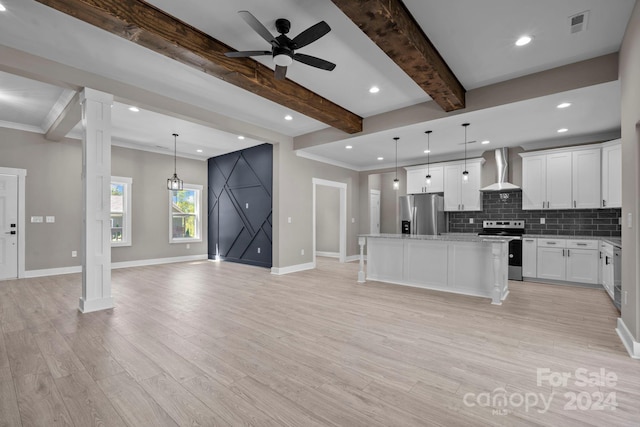 kitchen featuring appliances with stainless steel finishes, white cabinets, wall chimney exhaust hood, pendant lighting, and a center island