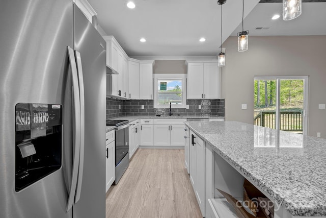 kitchen featuring light stone counters, a wealth of natural light, appliances with stainless steel finishes, and white cabinetry