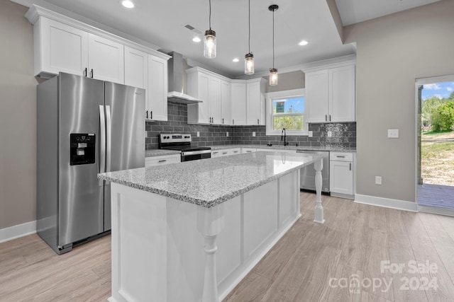 kitchen with stainless steel appliances, white cabinets, a center island, and wall chimney range hood