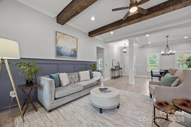 living room featuring ceiling fan with notable chandelier, beamed ceiling, and light wood-type flooring