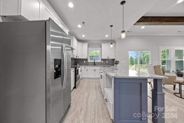 kitchen featuring light wood-type flooring, light stone counters, white cabinetry, hanging light fixtures, and appliances with stainless steel finishes