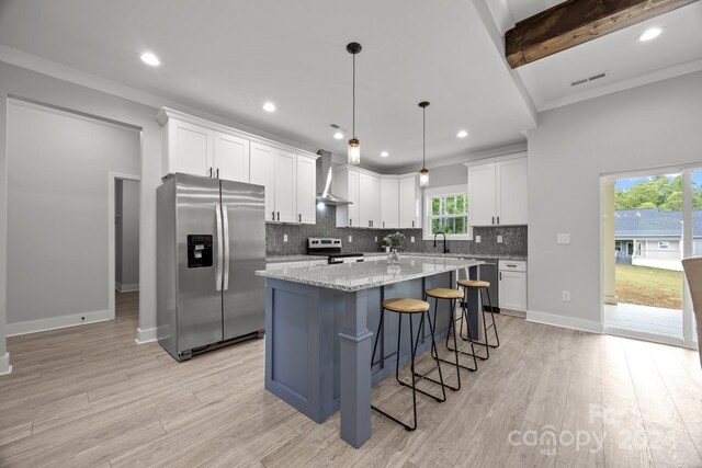 kitchen featuring appliances with stainless steel finishes, light hardwood / wood-style floors, white cabinetry, beamed ceiling, and a kitchen island with sink