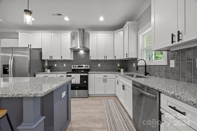 kitchen featuring white cabinets, sink, wall chimney exhaust hood, appliances with stainless steel finishes, and light wood-type flooring