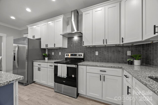 kitchen with stainless steel appliances, white cabinets, light hardwood / wood-style floors, and wall chimney range hood