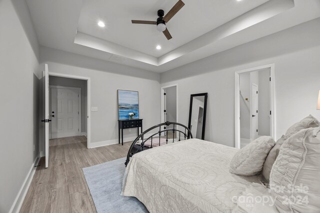 bedroom featuring a tray ceiling, light hardwood / wood-style floors, and ceiling fan