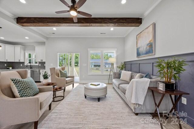 living room featuring ceiling fan, ornamental molding, sink, beam ceiling, and light hardwood / wood-style floors