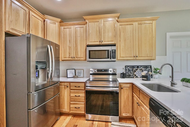 kitchen featuring sink, stainless steel appliances, light brown cabinets, and light hardwood / wood-style flooring