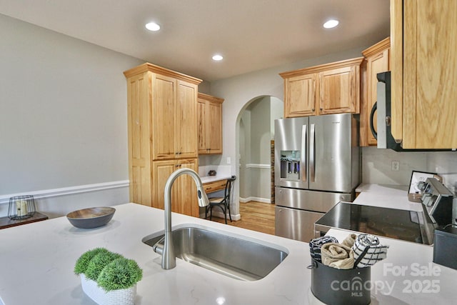 kitchen with range, sink, stainless steel refrigerator with ice dispenser, and light brown cabinets