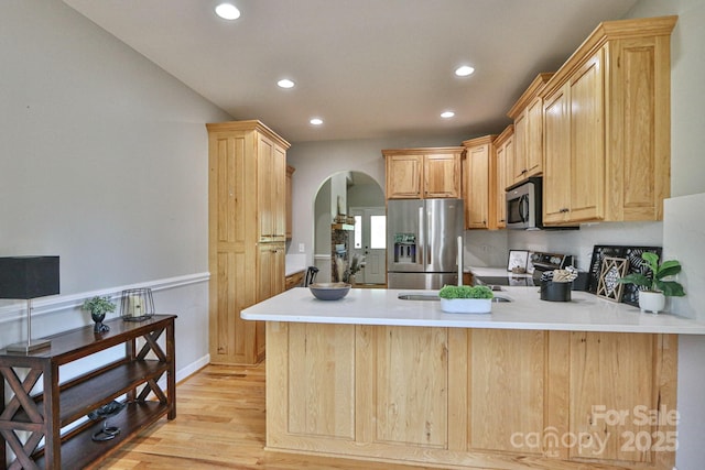 kitchen with kitchen peninsula, appliances with stainless steel finishes, light hardwood / wood-style flooring, and light brown cabinetry