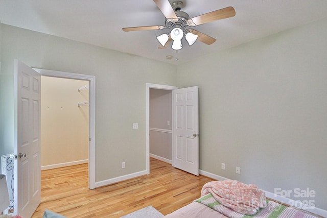 bedroom featuring hardwood / wood-style floors, a closet, a spacious closet, and ceiling fan