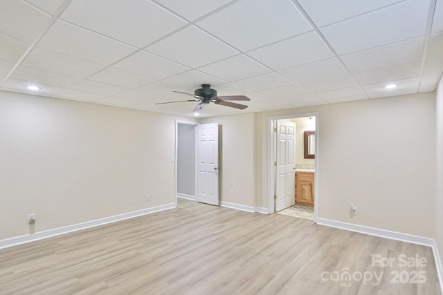 interior space with ceiling fan, a drop ceiling, and light wood-type flooring