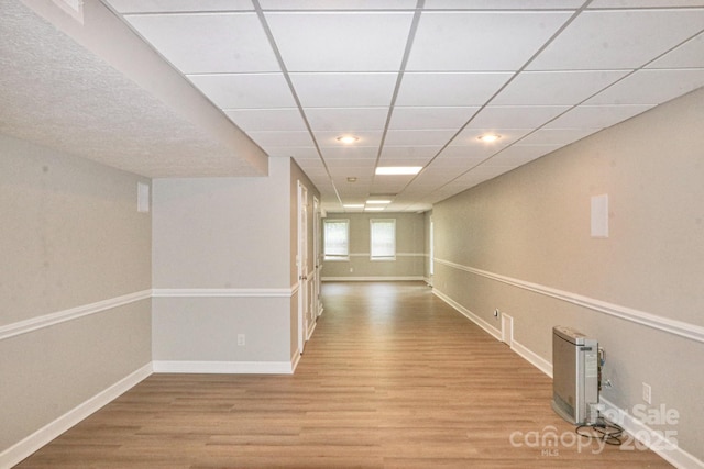 hall with a paneled ceiling and light wood-type flooring