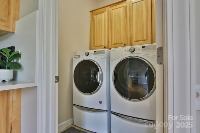 clothes washing area with cabinets and washing machine and dryer