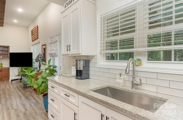 kitchen with light wood-type flooring, decorative backsplash, white cabinetry, and sink